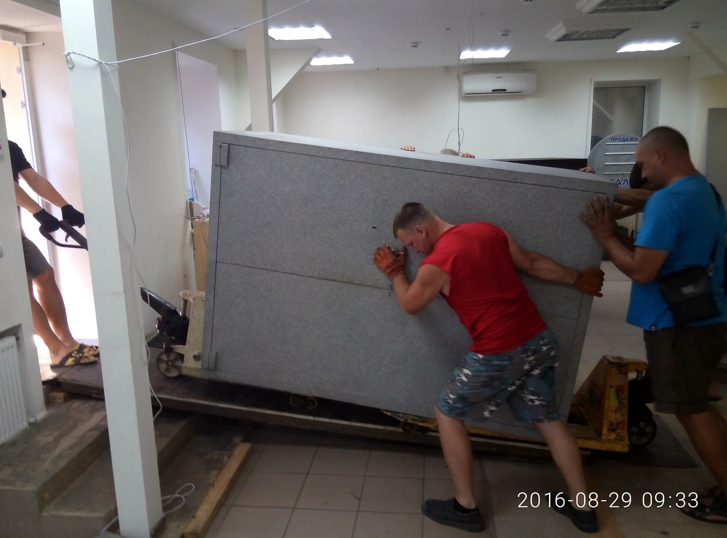 Грузчики перемещают сейф в офисе